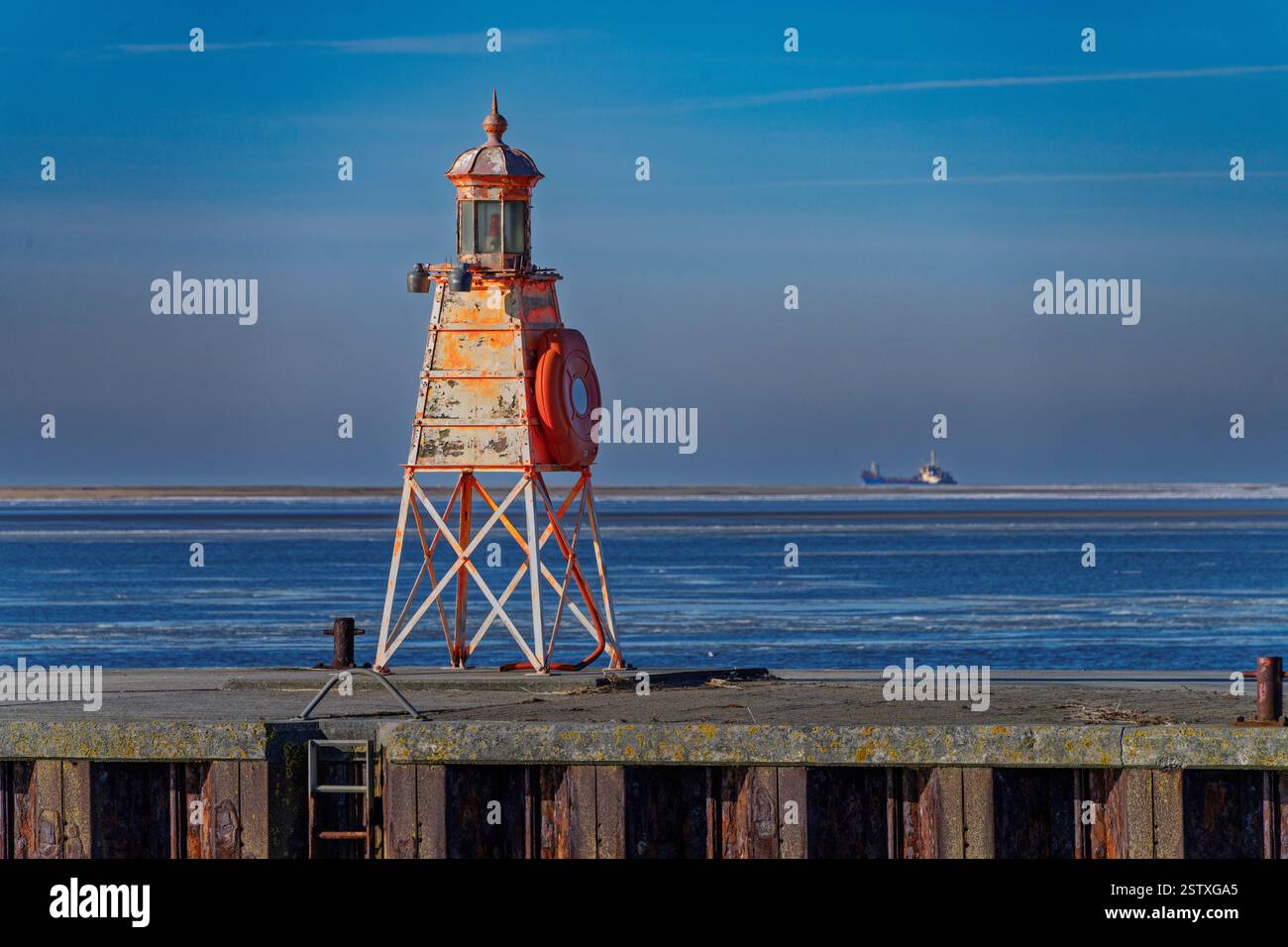 Una struttura industriale in vibranti colori verdi in un porto con acque calme. Installazioni industriali e un cielo azzurro sullo sfondo accentua Foto Stock