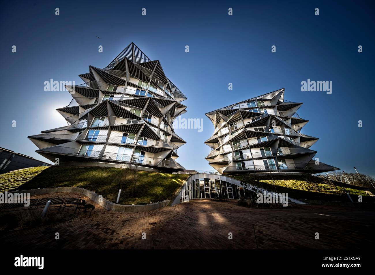 Un'architettura moderna unica e sorprendentemente angolata posta su un cielo azzurro e vivace, presenta un design innovativo e un'audace estetica urbana. Foto Stock