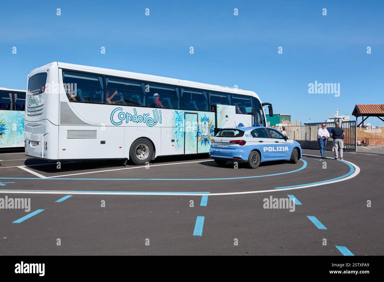 Catania, Italia - 20 febbraio 2025: Autobus turistico parcheggiato presso un terminal della città. E un'auto della polizia e' nelle vicinanze, indicando un controllo di sicurezza. Ideale per i viaggi Foto Stock