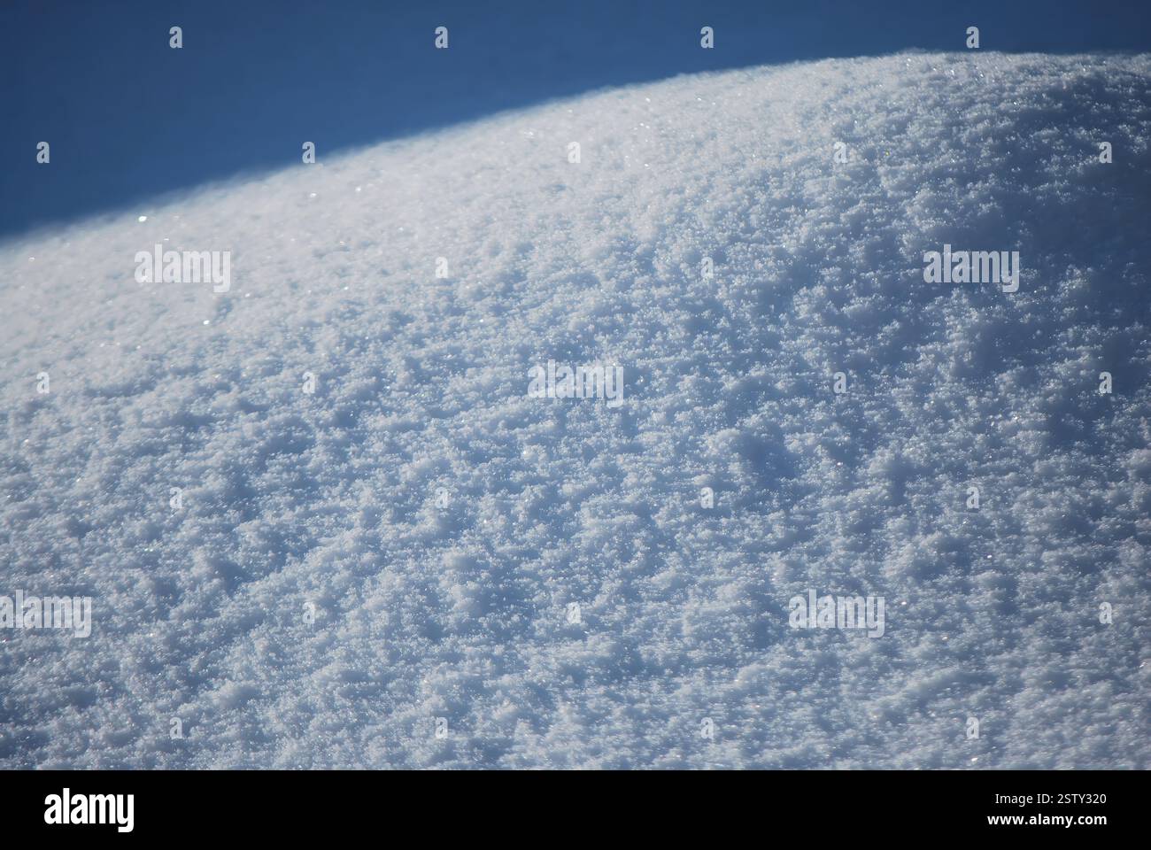 Vista ravvicinata della neve appena caduta che splende alla luce del sole, un'ombra visibile sullo sfondo Foto Stock