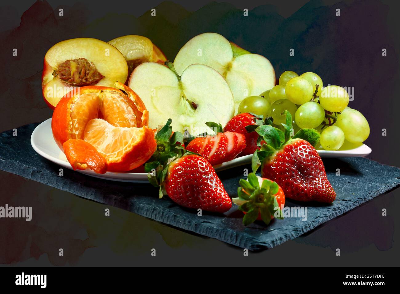 Vista ravvicinata di una collezione di frutti diversi stesi su un'ardesia con uno sfondo fantasioso. Foto Stock