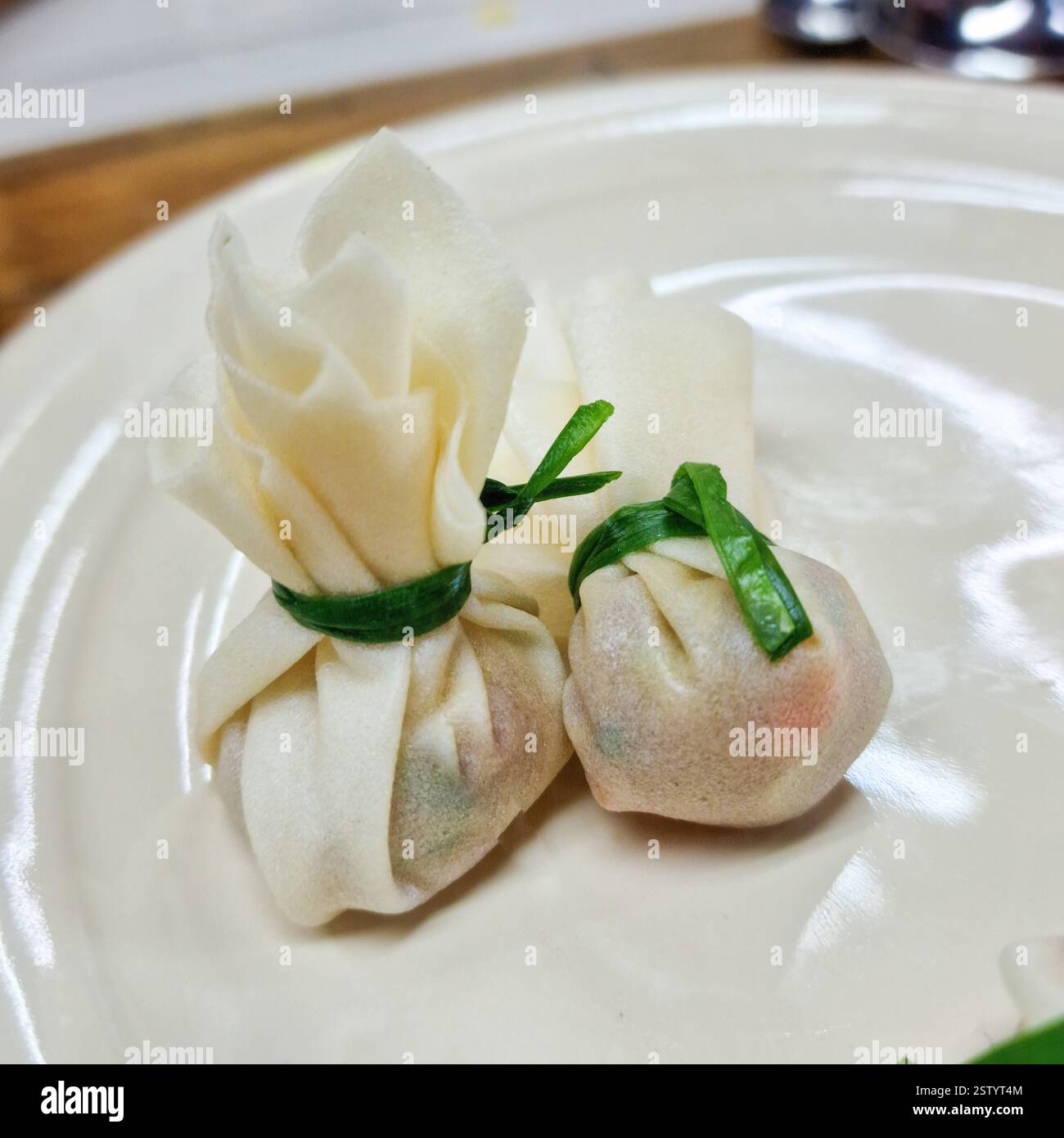 Due gnocchi delicati, avvolti in un impasto sottile e legati con erba cipollina Foto Stock