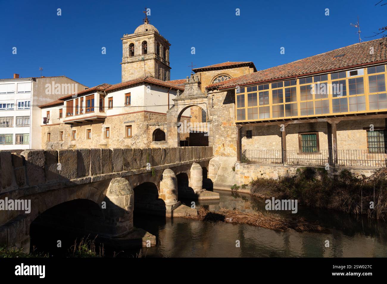 Il campanile della chiesa di San Miguel e il ponte e la porta di Portazgo nel villaggio storico di Aguilar de Campoo, Palencia, in Spagna, in una giornata di sole. Foto Stock