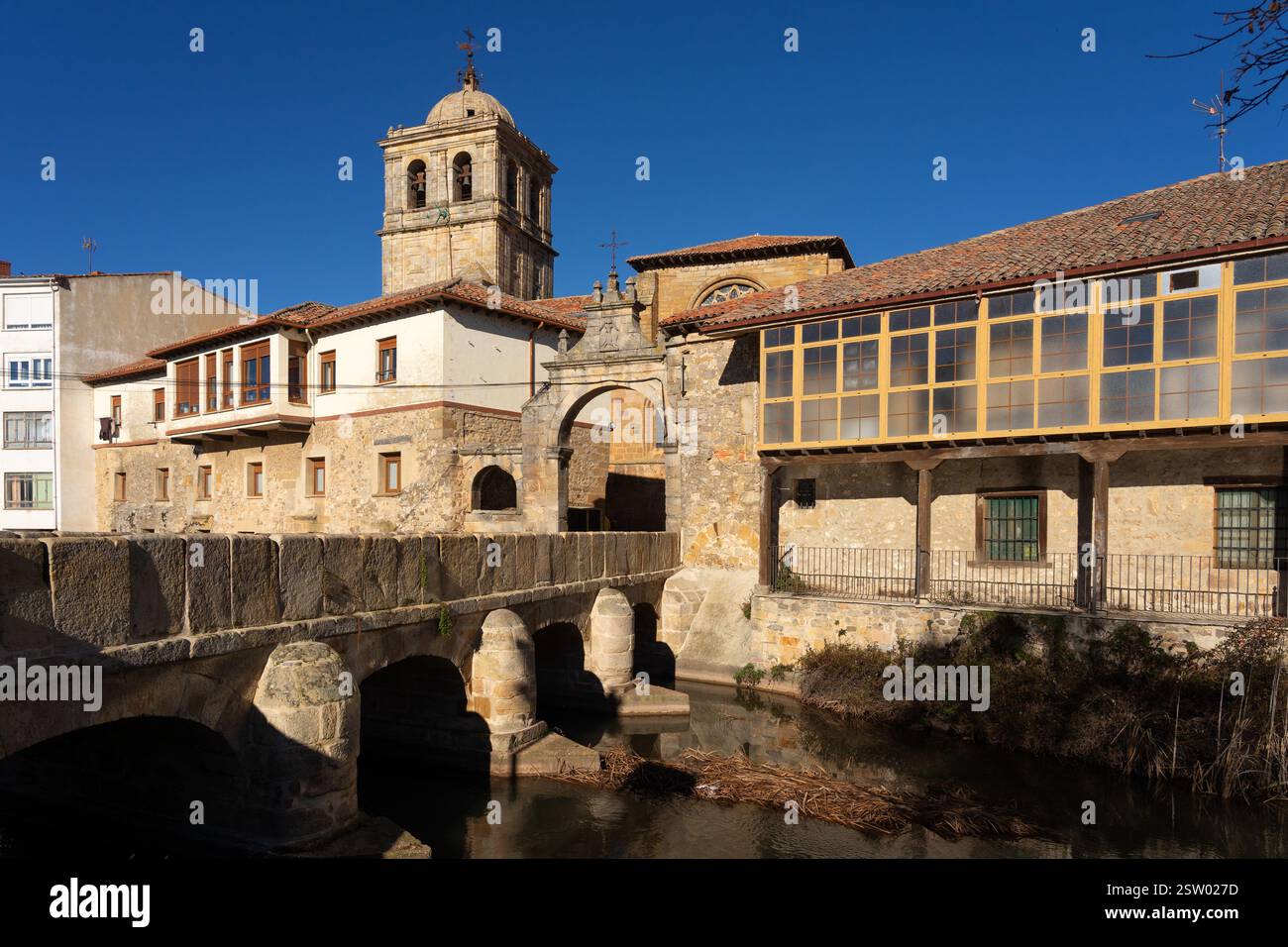 Il campanile della chiesa di San Miguel e il ponte e la porta di Portazgo nel villaggio storico di Aguilar de Campoo, Palencia, in Spagna, in una giornata di sole. Foto Stock