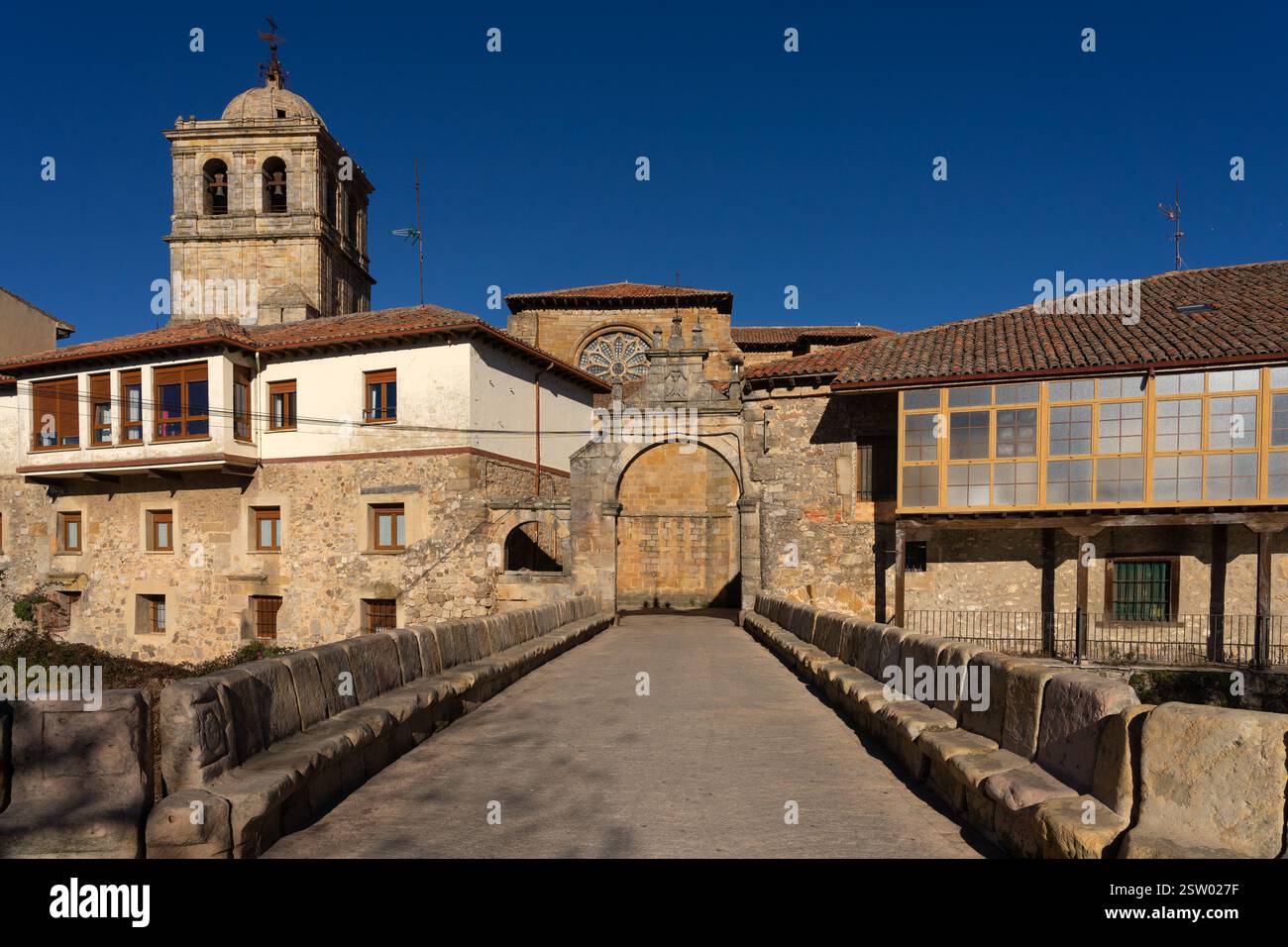 Il campanile della chiesa di San Miguel e il ponte e la porta di Portazgo nel villaggio storico di Aguilar de Campoo, Palencia, in Spagna, in una giornata di sole. Foto Stock