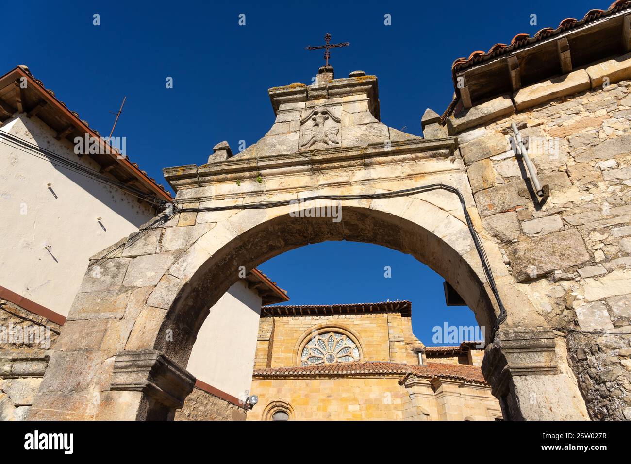Il campanile della chiesa di San Miguel e il ponte e la porta di Portazgo nel villaggio storico di Aguilar de Campoo, Palencia, in Spagna, in una giornata di sole. Foto Stock