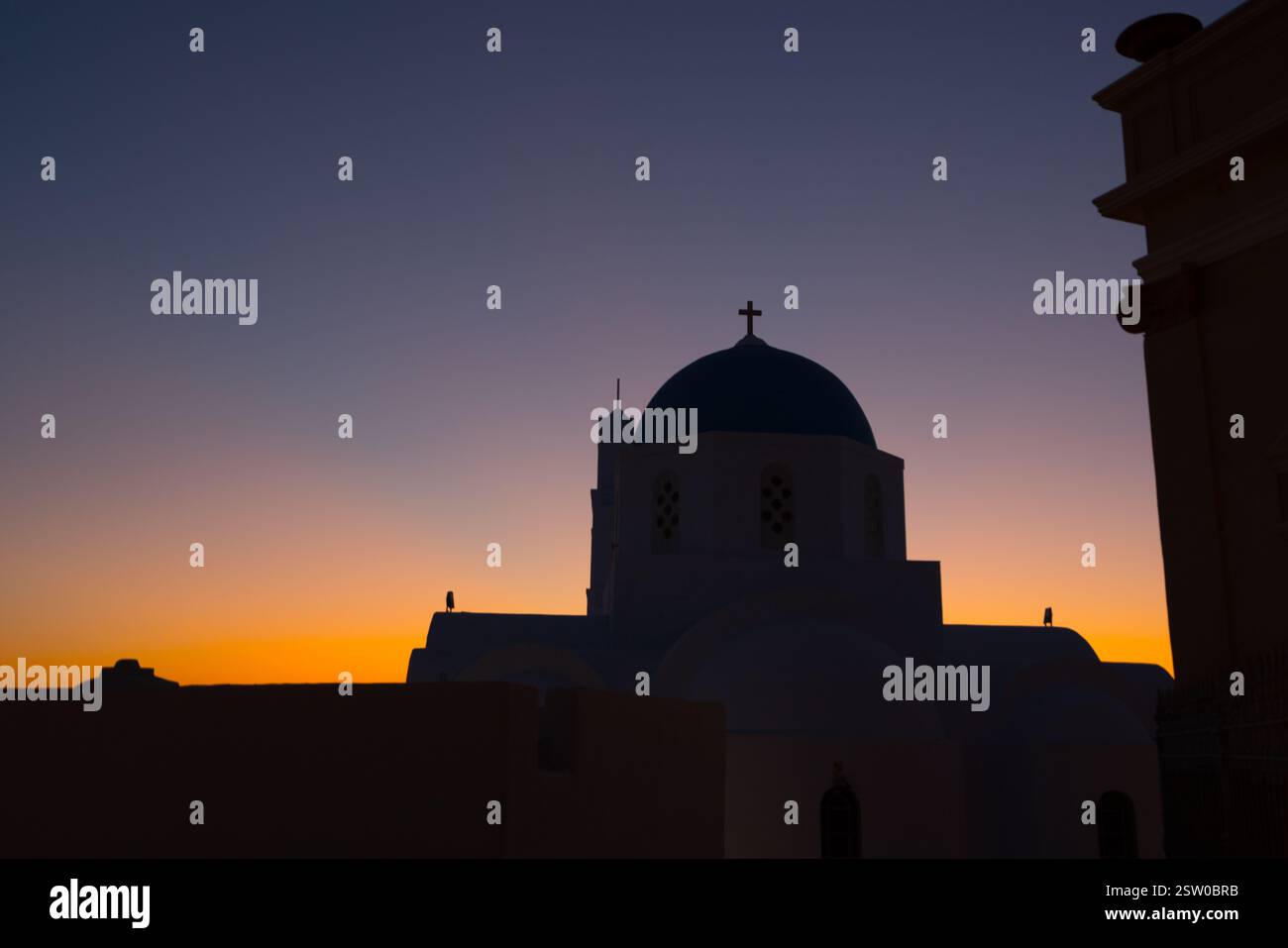 Sagoma della chiesa a Pyrgos contro il cielo serale con tonalità arancio e blu Foto Stock