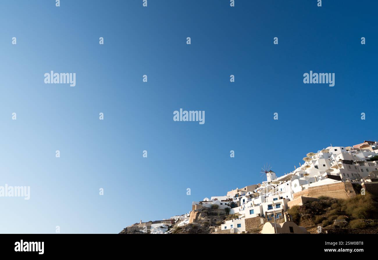 Grande cielo azzurro senza nuvole sopra una piccola area di case bianche di Oia santorini Foto Stock