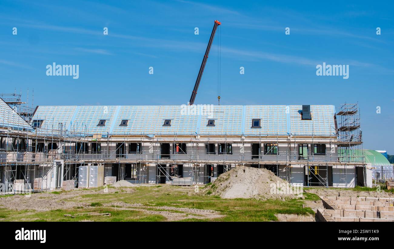 Le moderne case familiari sorgono nel cantiere dei sobborghi olandesi sotto il cielo azzurro Foto Stock