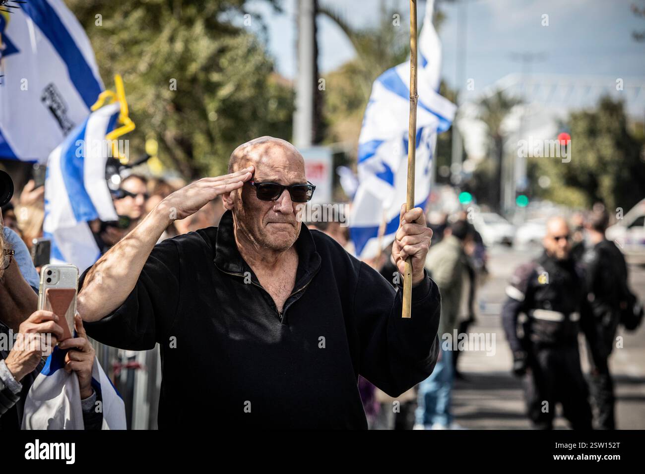 Tel Aviv, 20 febbraio 2025. Un saluto da uomo che mostra il suo rispetto per il convoglio che trasporta i corpi degli ostaggi israeliani fuori dal Centro Nazionale di Medicina legale Abu Kabir a Tel Aviv giovedì 20 febbraio 2025. Hamas ha rilasciato giovedì i corpi di quattro ostaggi israeliani, i resti si diceva fossero di Shiri Bibas e dei suoi due figli, Ariel e Kfir, così come di Oded Lifshitz, che aveva 83 anni quando è stato rapito. Hamas ha detto che tutti e quattro sono stati uccisi insieme alle loro guardie in un attacco aereo israeliano. Foto di Eyal Warshavsky. Foto Stock