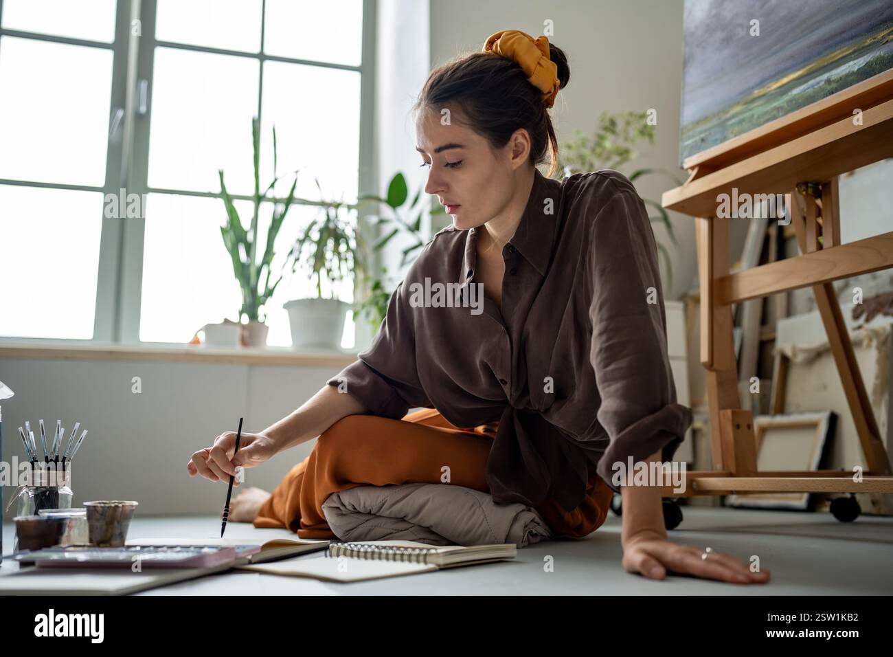 Donna artistica ispirata, piena di idee, incarna fantasie nel disegno, disegna con aquarelle Foto Stock