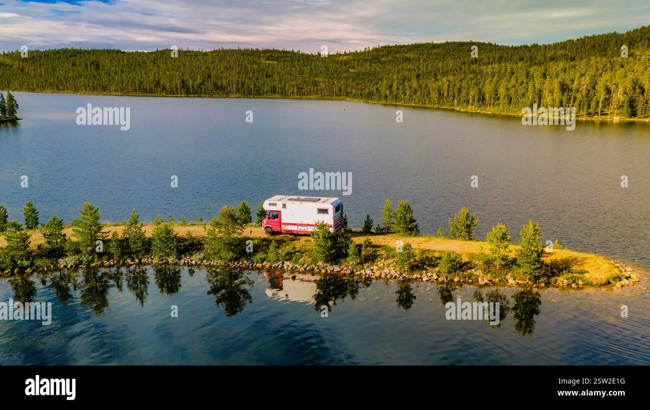 Camper parcheggiata presso il tranquillo lago annidato nel paesaggio selvaggio mozzafiato di Norways Foto Stock