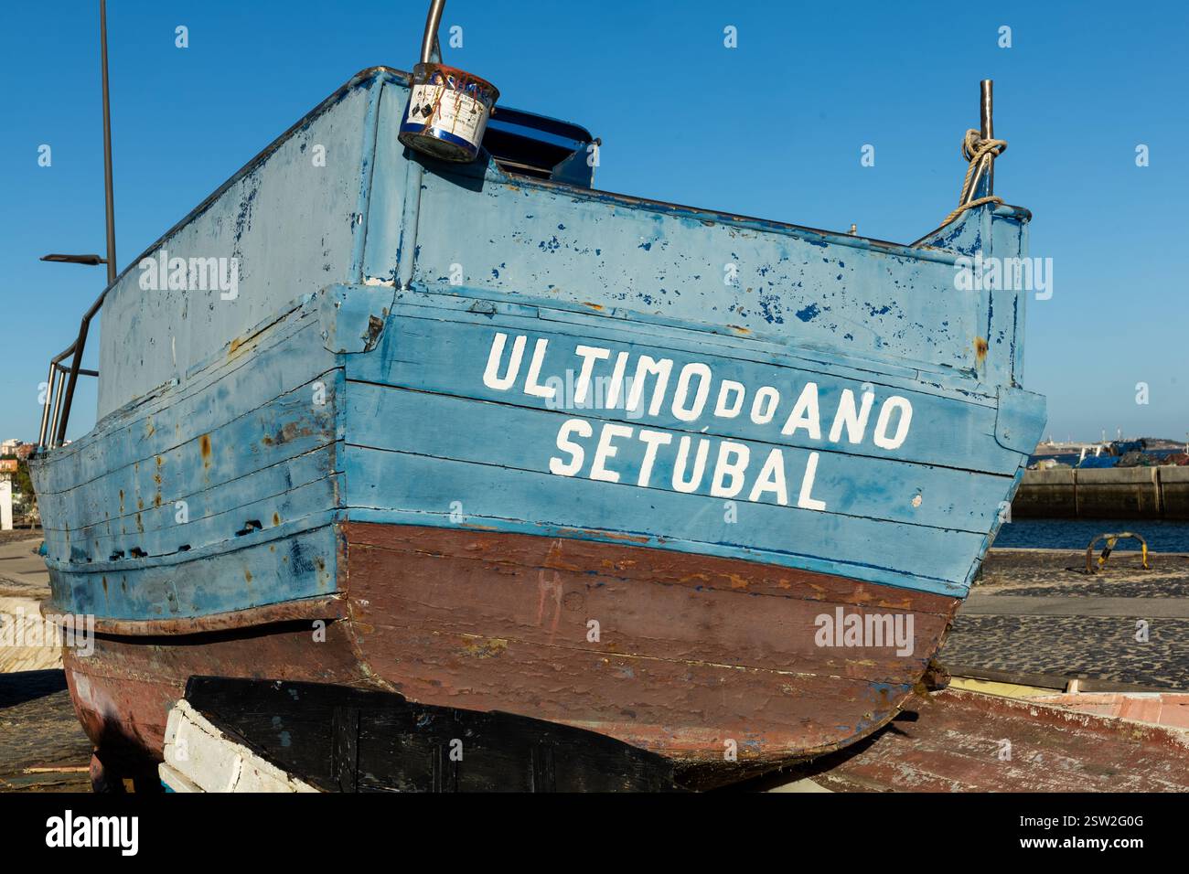 Piccola barca da pesca tradizionale sulla banchina per riparazioni e verniciatura. Nome della barca “ultimo do Ano Setúbal” in inglese “Last of the Year Setúbal” Foto Stock