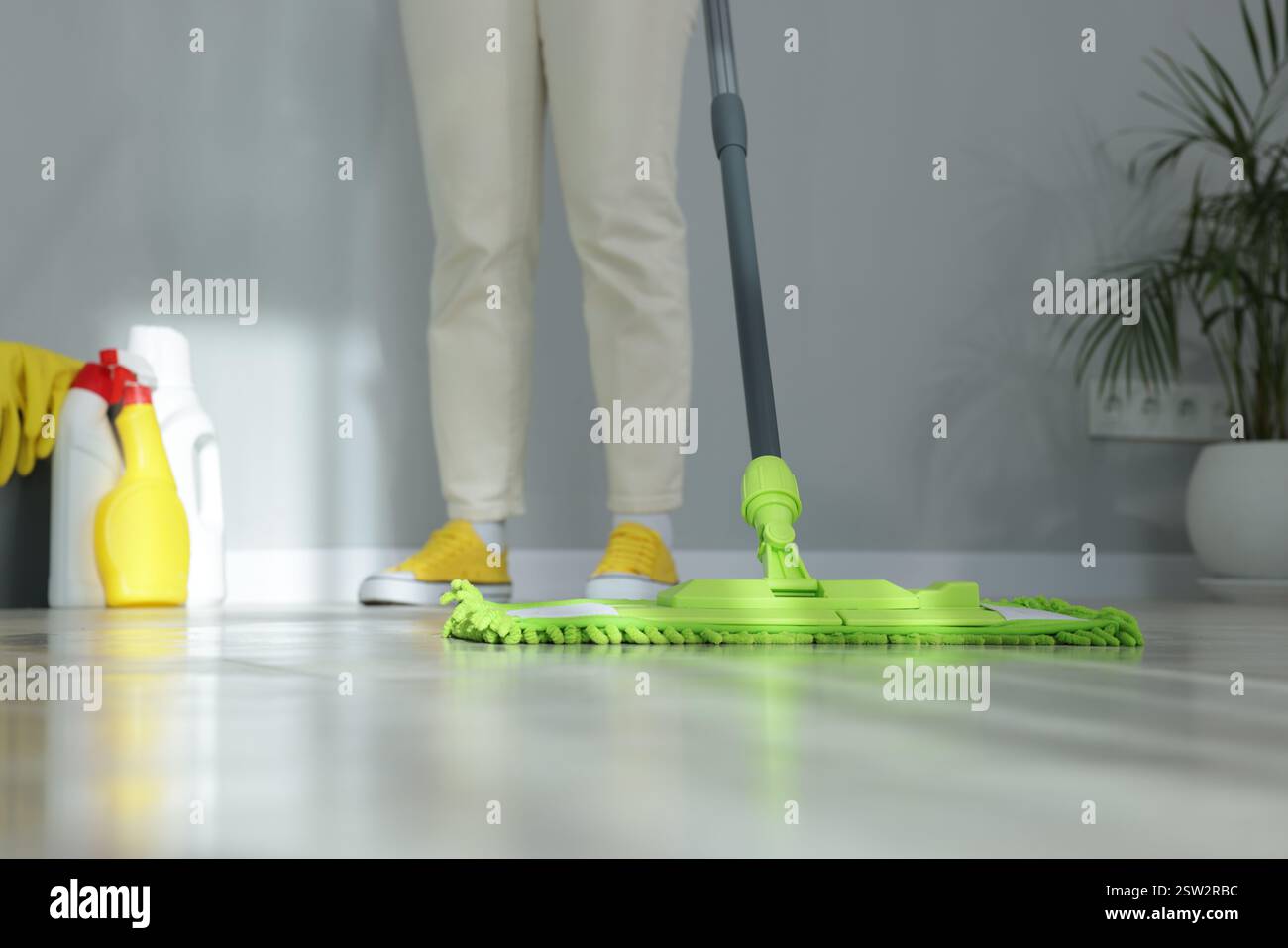 Donna che pulisce il pavimento con mocio in microfibra in interni, primo piano Foto Stock