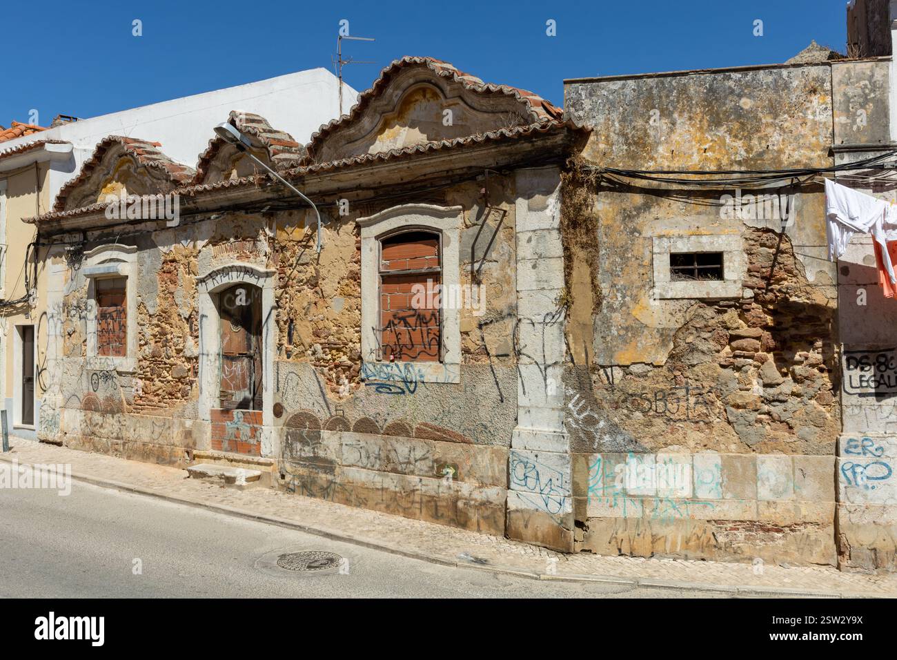 Una vecchia casa abbandonata in una strada con finestre in mattoni e porta d'ingresso. Ornamenti ancora presenti. Foto Stock