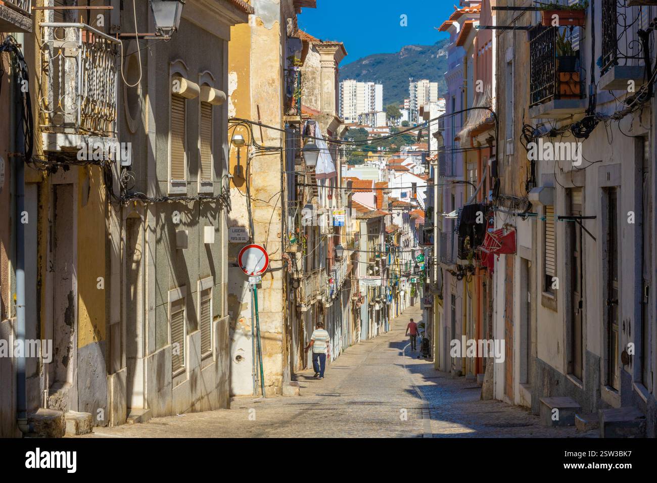 Una tipica vecchia strada europea, stretta con i suoi antichi edifici, la città europea. Un paesaggio urbano di Setúbal con minuscoli negozi e caffetterie. Foto Stock
