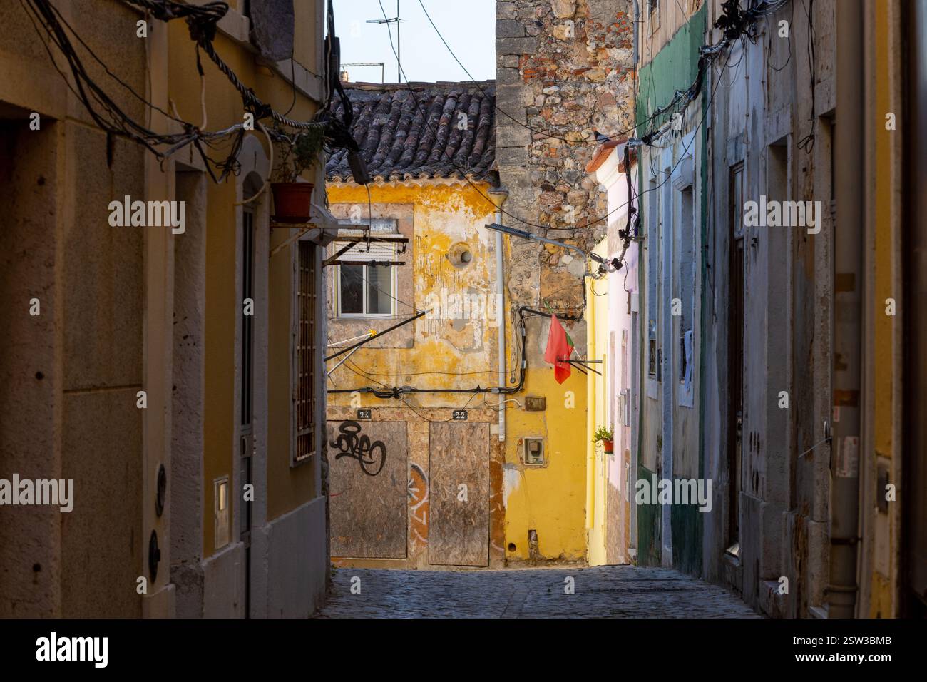 Una tipica vecchia strada europea, stretta con i suoi antichi edifici, la città europea. Un paesaggio urbano di Setúbal con minuscoli negozi e caffetterie. Foto Stock