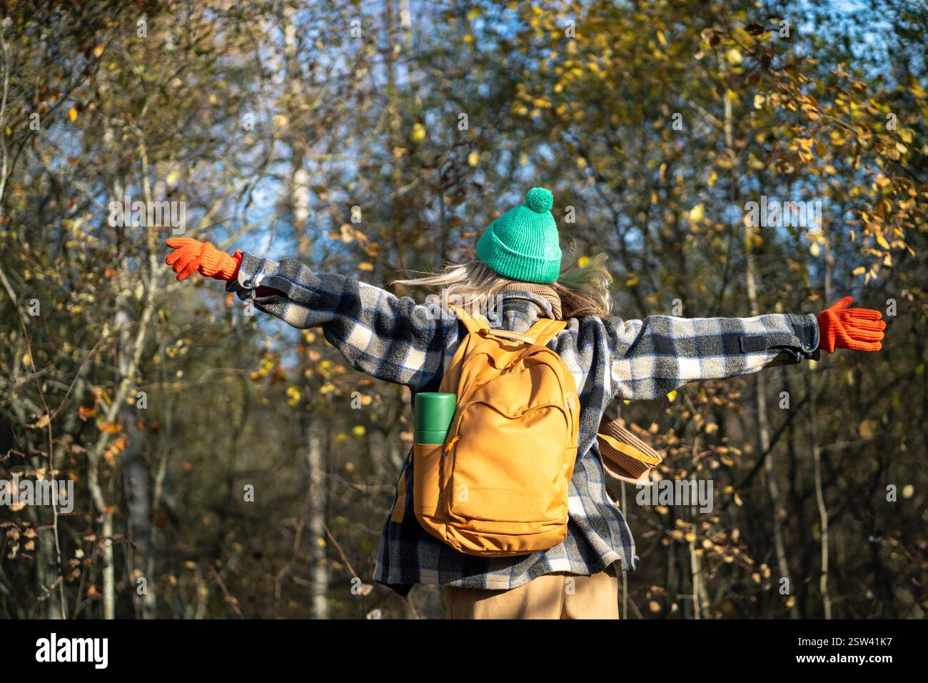 Donna libera e felice che cammina nella foresta con le braccia allungate, mani sparse ai lati in piacere. Foto Stock