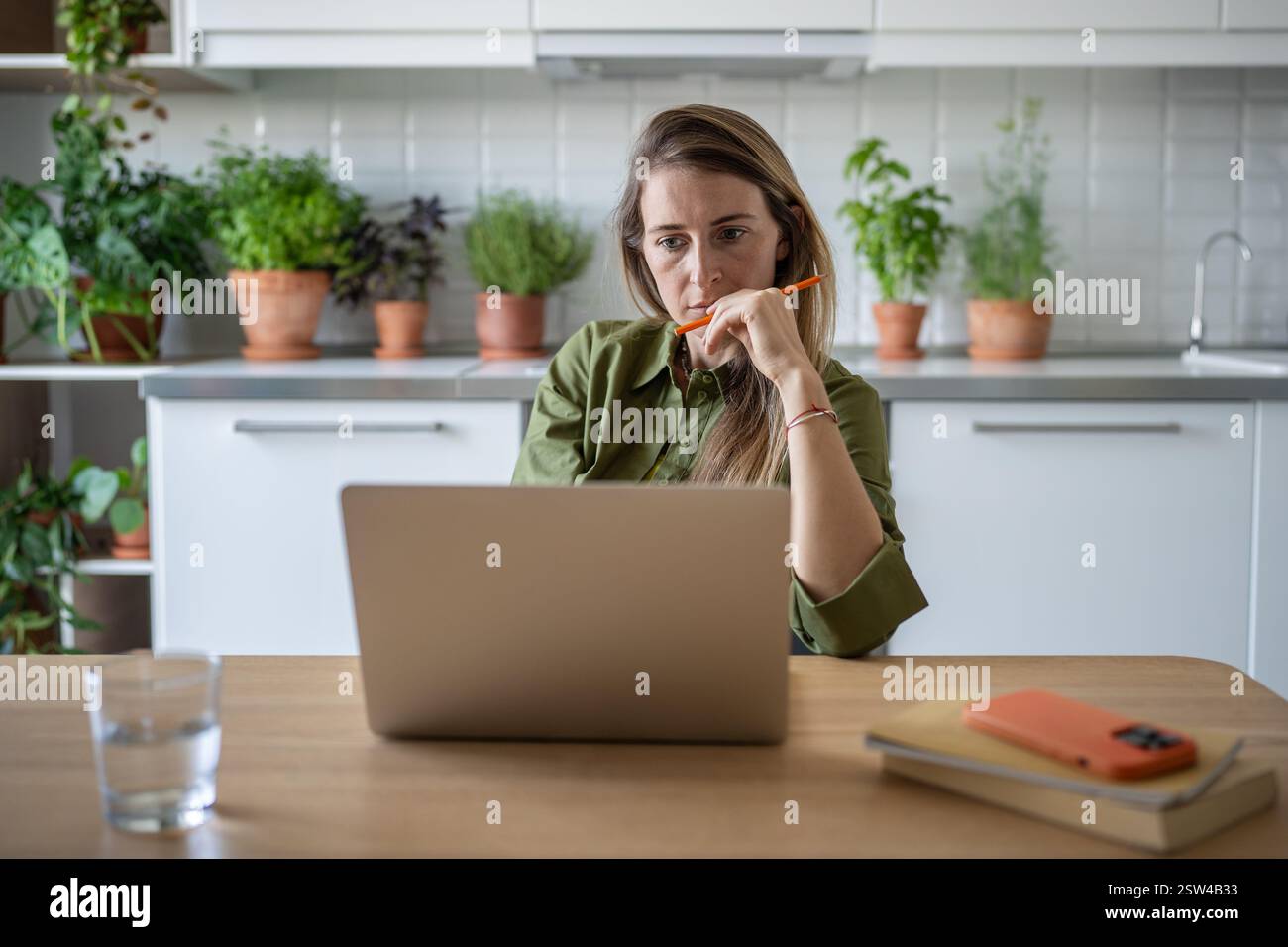 Donna penosa freelance che lavora con un notebook si è concentrata sul progetto a casa con efficienza e dedizione. Foto Stock