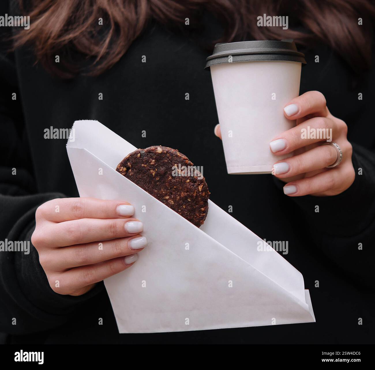 Donna che tiene in mano una tazza di caffè e biscotti d'avena Foto Stock