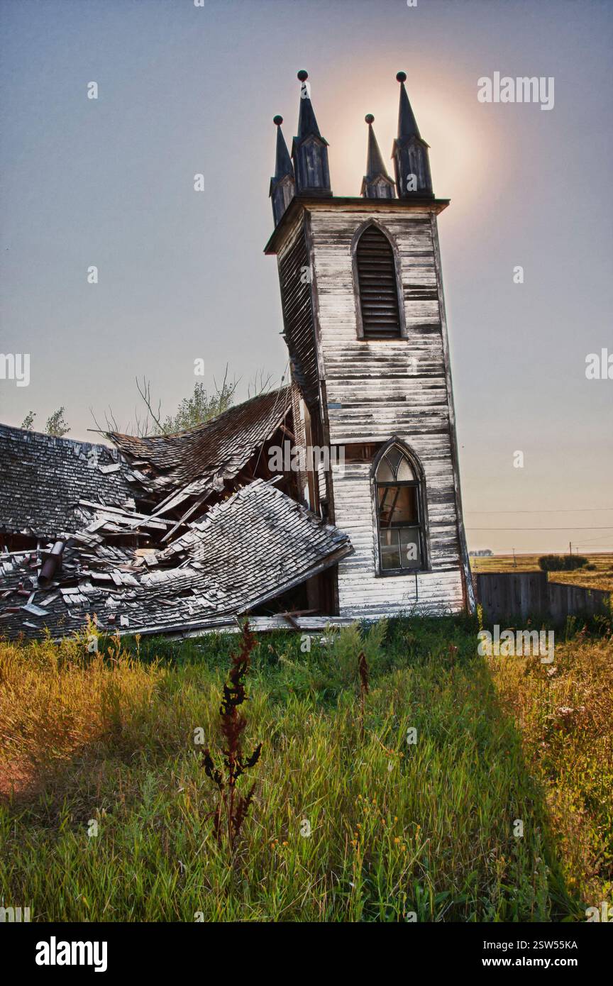 La chiesa è ripida con un tetto rotto e una finestra. La chiesa è vecchia e abbandonata. Il sole splende sulla chiesa, rendendola ancora più desolata Foto Stock