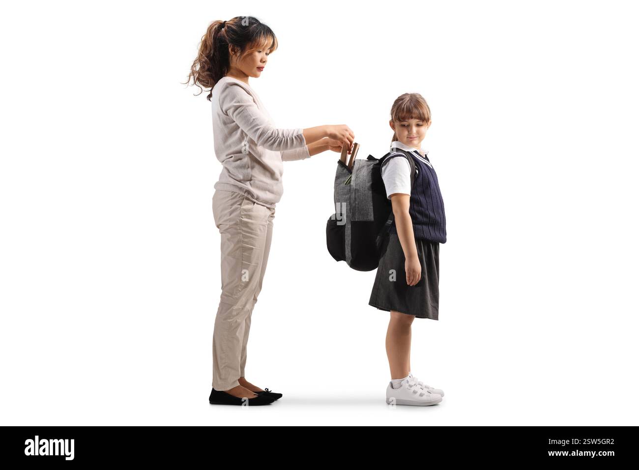 Donna asiatica che aiuta una ragazza con lo zaino della scuola isolato su sfondo bianco Foto Stock