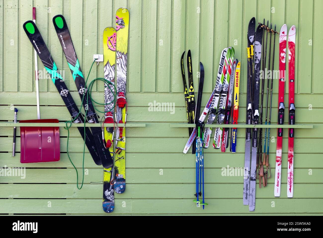 Longyearbyen, Svalbard - 22 maggio 2019: Sci di famiglia su una cremagliera su una parete esterna. Forme, dimensioni e design diversi, con pali e una pala da neve Foto Stock