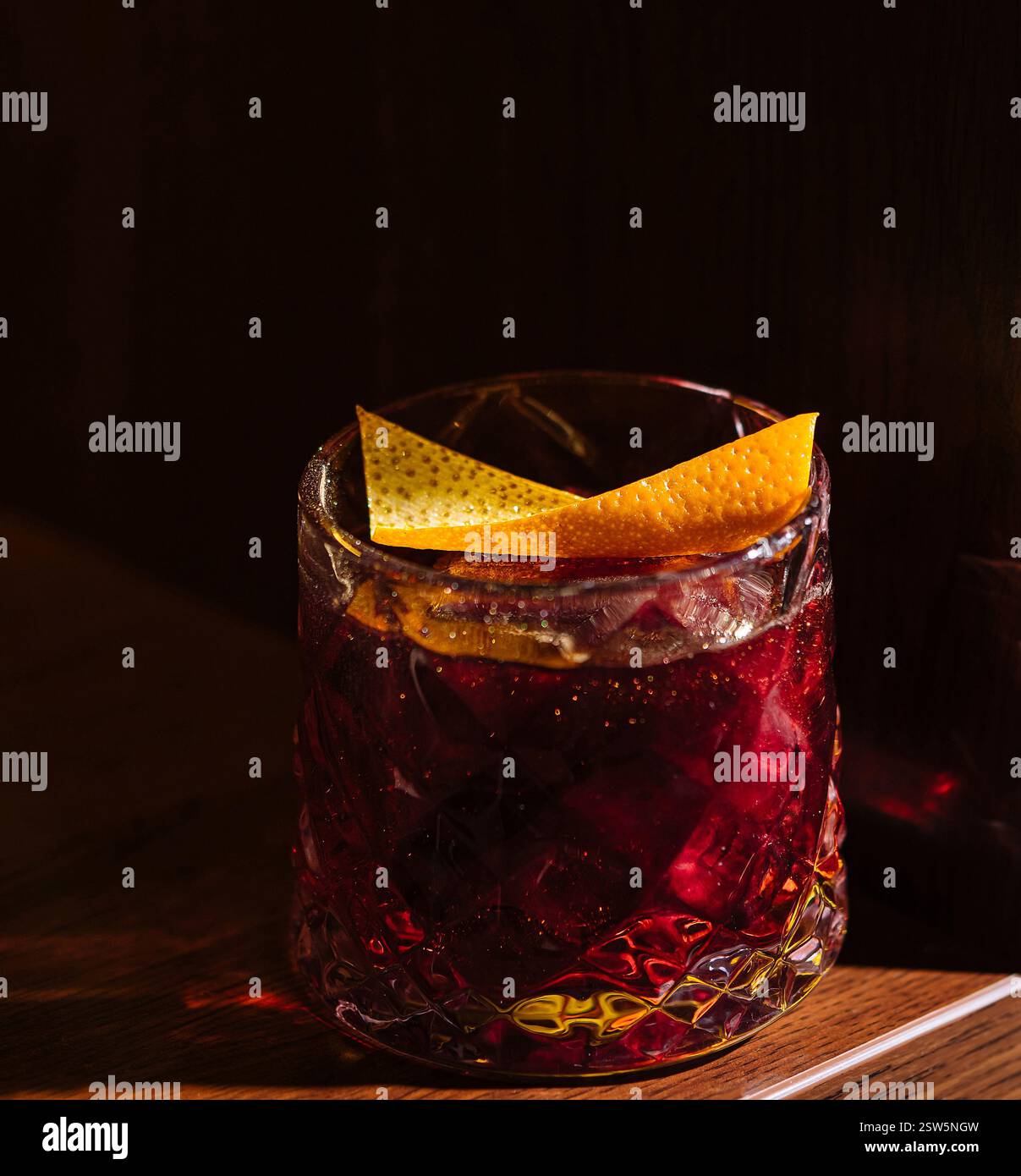 Elegante cocktail con guarnizione di agrumi in un'illuminazione soffusa Foto Stock