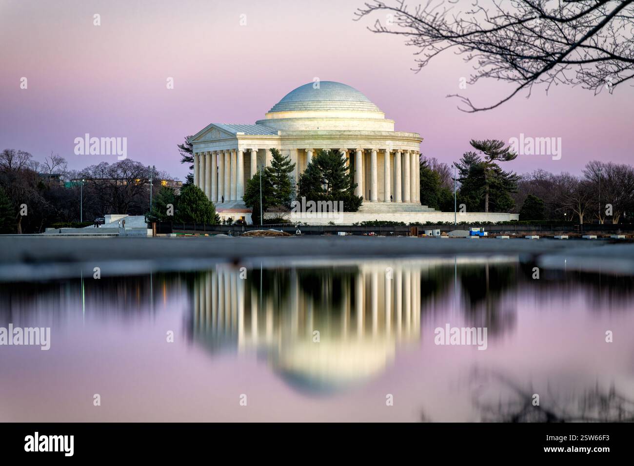 WASHINGTON DC - il Thomas Jefferson Memorial è illuminato con luce rosa al crepuscolo, mentre si riflette sulle acque tranquille del bacino delle maree. Il monumento neoclassico, dedicato nel 1943, crea un'immagine speculare sulla superficie dell'acqua. Le sfumature rosa del tramonto bagnano la struttura in marmo bianco in una calda luce soffusa contro il cielo serale. Foto Stock