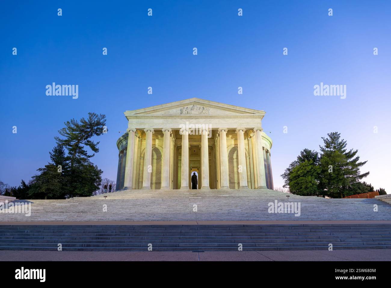 WASHINGTON DC: La facciata anteriore e i gradini del Thomas Jefferson Memorial sono illuminati al crepuscolo lungo il bacino delle maree. Il monumento neoclassico presenta un portico con colonne ioniche che sostengono un tetto a cupola. Progettato dall'architetto John Russell Pope, il memoriale è stato dedicato nel 1943 in onore del terzo presidente americano. Foto Stock