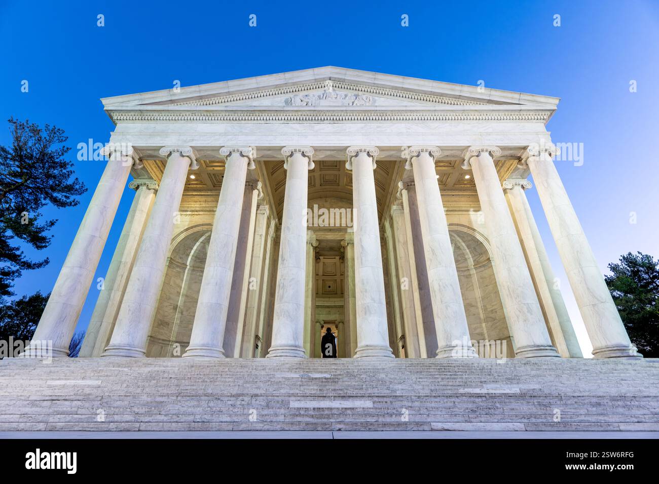 WASHINGTON DC: La facciata anteriore e i gradini del Thomas Jefferson Memorial sono illuminati al crepuscolo lungo il bacino delle maree. Il monumento neoclassico presenta un portico con colonne ioniche che sostengono un tetto a cupola. Progettato dall'architetto John Russell Pope, il memoriale è stato dedicato nel 1943 in onore del terzo presidente americano. Foto Stock