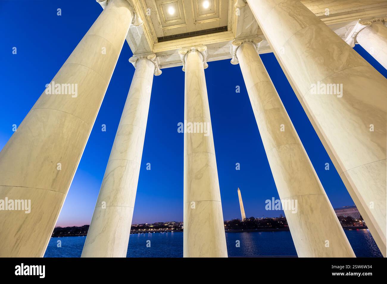WASHINGTON DC - il Washington Monument è incorniciato dalle colonne di marmo del Thomas Jefferson Memorial al crepuscolo. Il bacino delle maree si estende tra i due monumenti iconici del National Mall. Il Jefferson Memorial, progettato dall'architetto John Russell Pope, fu dedicato nel 1943 in onore del terzo presidente degli Stati Uniti. Foto Stock