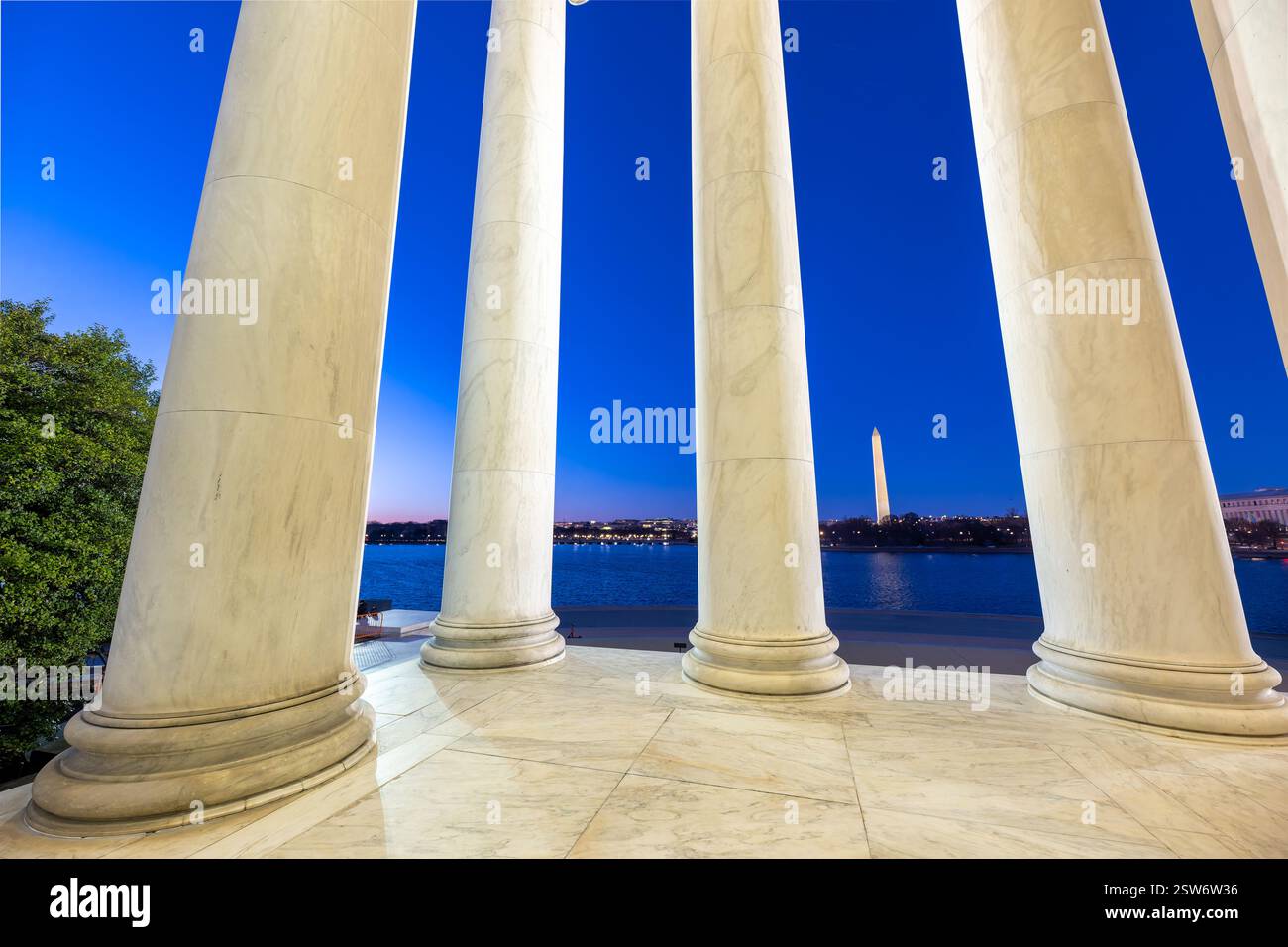 WASHINGTON DC - il Washington Monument è incorniciato dalle colonne di marmo del Thomas Jefferson Memorial al crepuscolo. Il bacino delle maree si estende tra i due monumenti iconici del National Mall. Il Jefferson Memorial, progettato dall'architetto John Russell Pope, fu dedicato nel 1943 in onore del terzo presidente degli Stati Uniti. Foto Stock