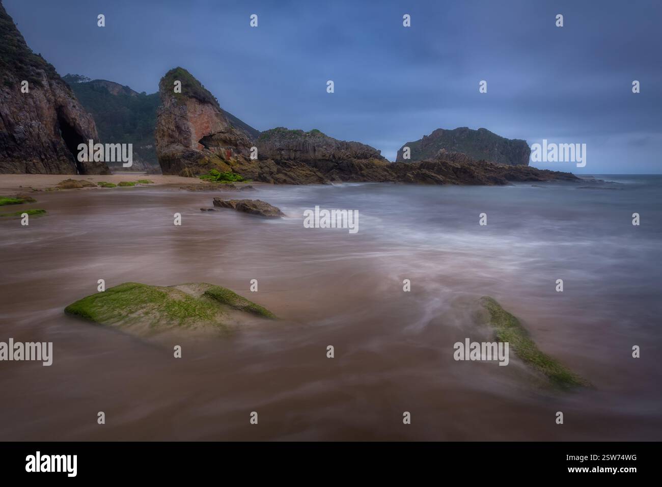Playa de la Franca: Paesaggio costiero mostruoso con rocce aspre, acqua liscia e pietre muschiate nelle Asturie, Spagna Foto Stock