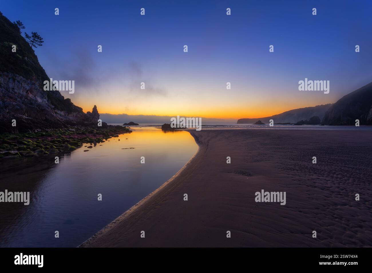 Playa de la Franca: Paesaggio costiero mostruoso con rocce aspre, acqua liscia e pietre muschiate nelle Asturie, Spagna Foto Stock