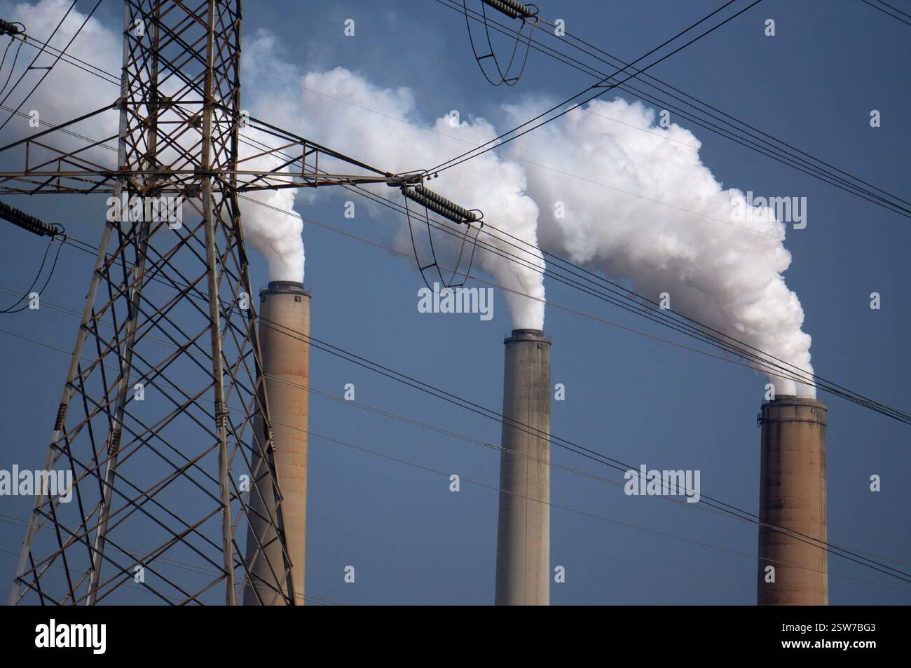 Centrale elettrica a carbone con infrastrutture elettriche che emettono fumo inquinante e vapore nel cielo dalle cisterne Foto Stock