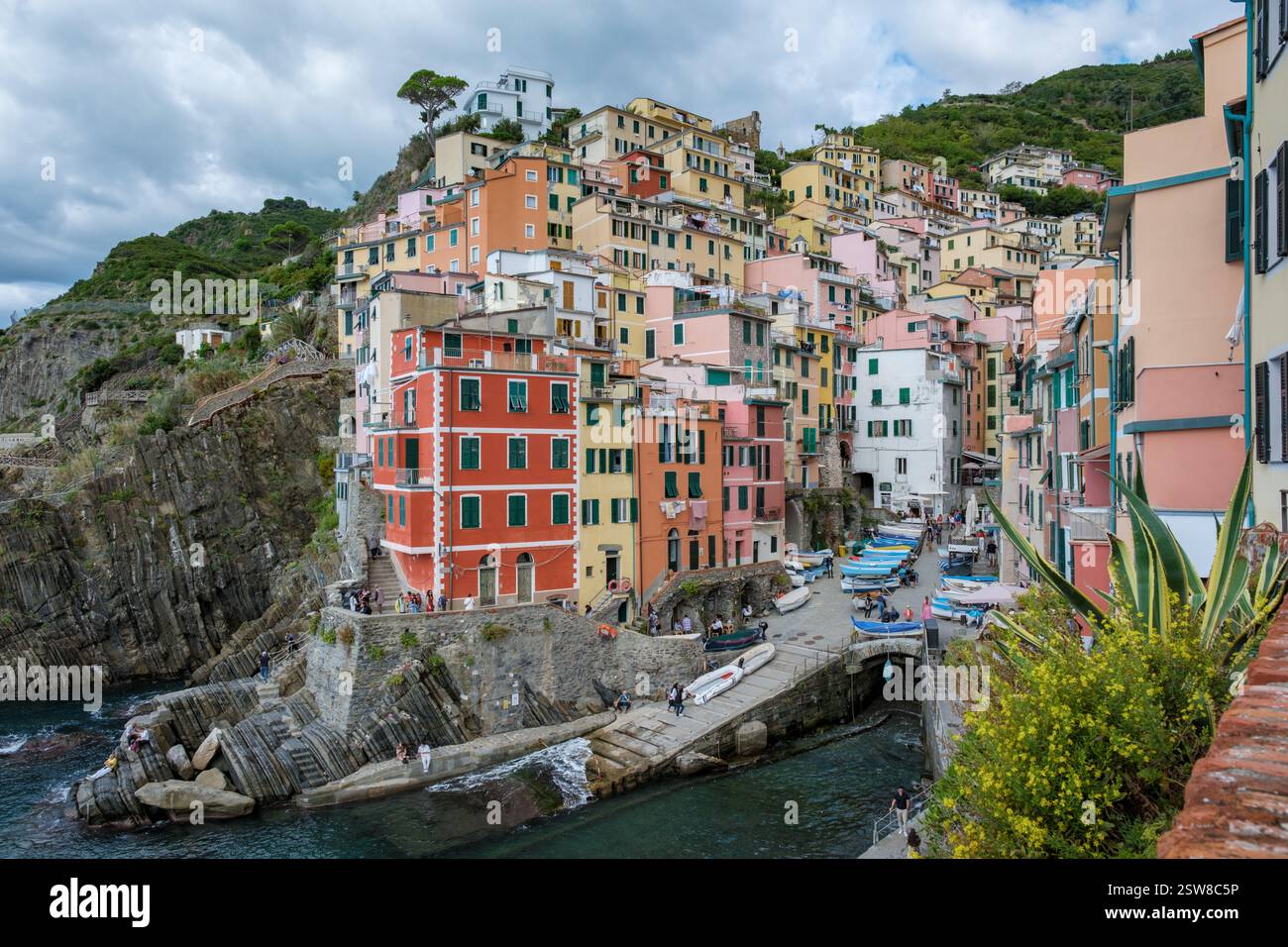 Case colorate che costeggiano le scogliere delle cinque Terre, con barche che riposano nel porto costiero Foto Stock