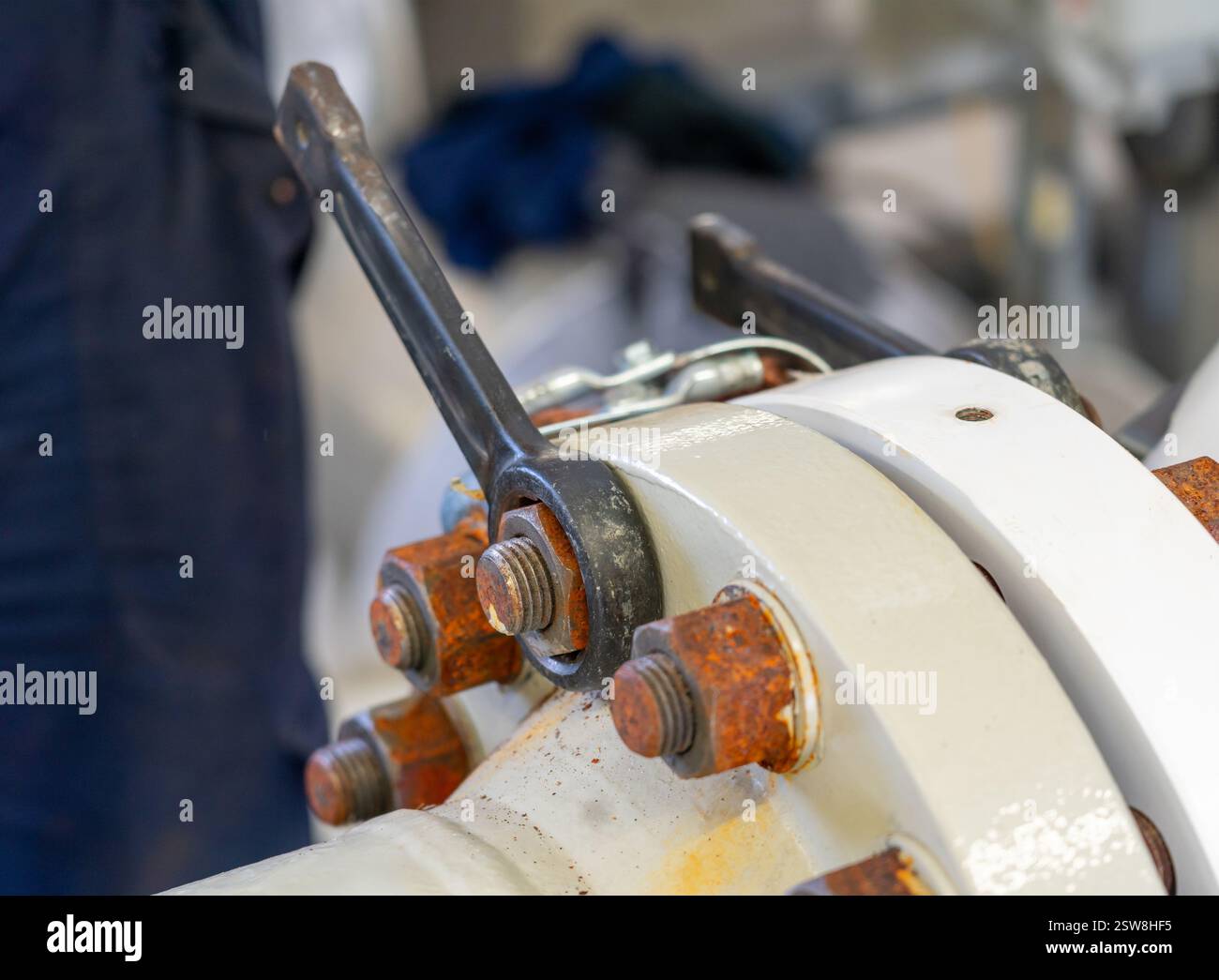 Primo piano di una flangia industriale con bulloni serrati con una chiave per un funzionamento sicuro e preciso Foto Stock