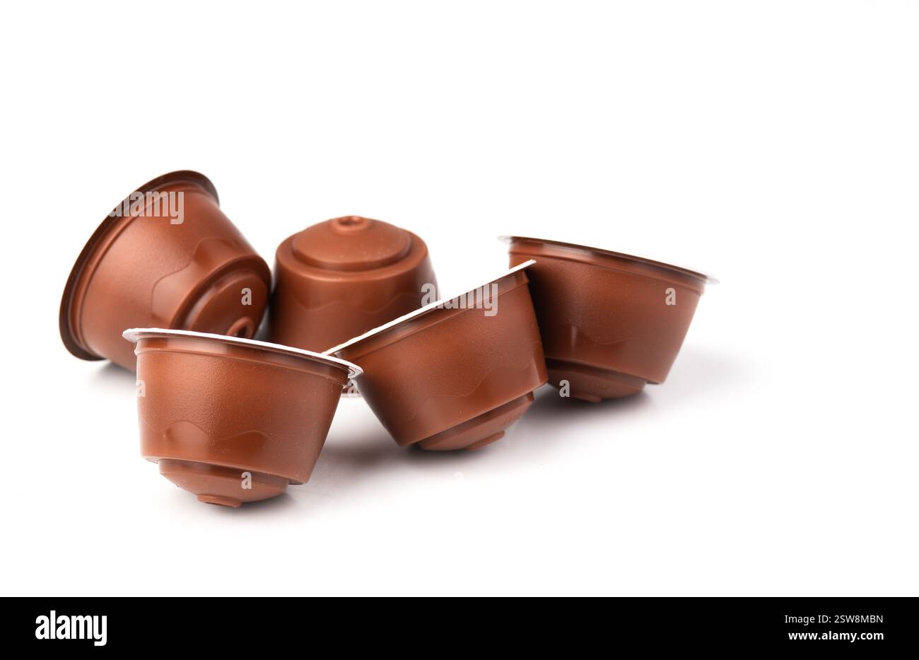 Capsule di caffè marroni su sfondo bianco. Cialde espresso in plastica per macchine da caffè. Foto Stock