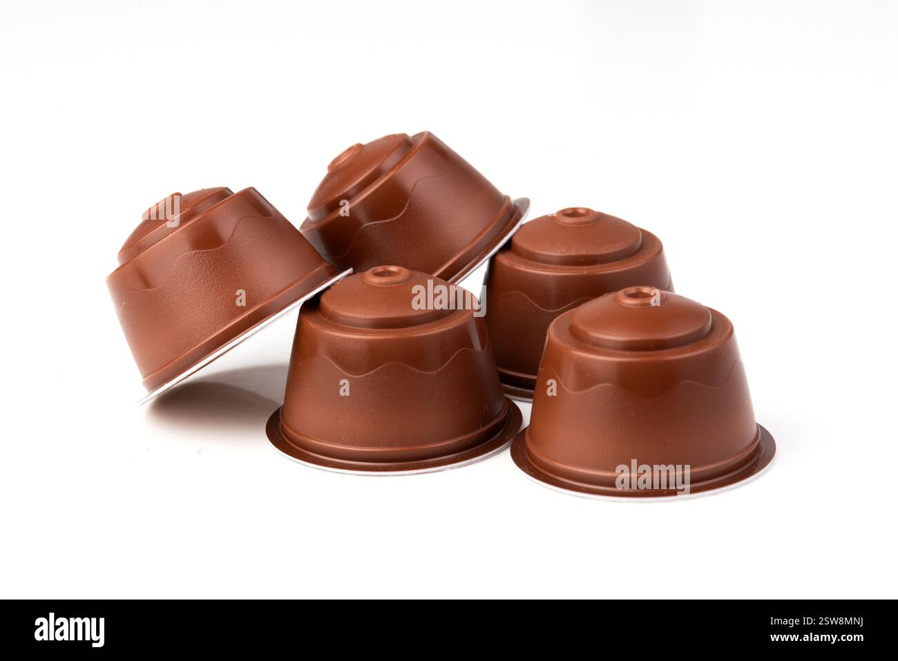 Capsule di caffè marroni su sfondo bianco. Cialde espresso in plastica per macchine da caffè. Foto Stock