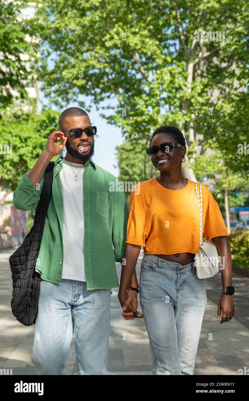 Una coppia afroamericana che ama camminare tenersi per mano in città e fare ridere la fidanzata. Foto Stock
