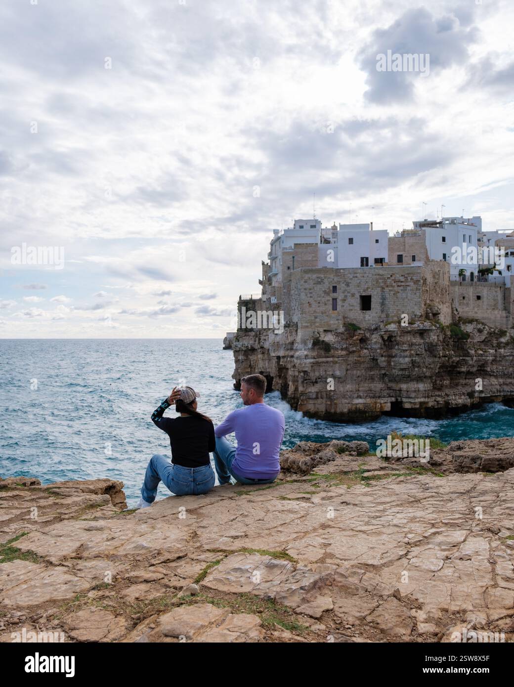 Passeggiando lungo la costa rocciosa della Puglia, Italia, mentre le nuvole si radunano sopra la testa al tramonto Foto Stock