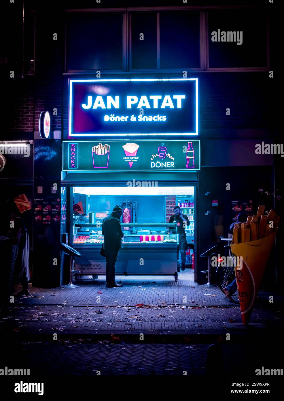 Un chiosco di patatine al neon illumina la notte, una sosta calda e invitante per le voglie notturne nel cuore della città Foto Stock