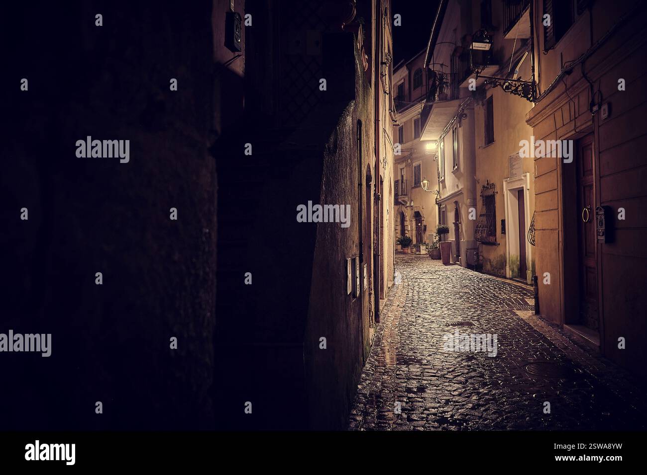 Un villaggio italiano abbandonato in una fredda notte invernale, dove il tempo sembra essersi fermato sotto il fiato bagliore degli antichi lampioni Foto Stock