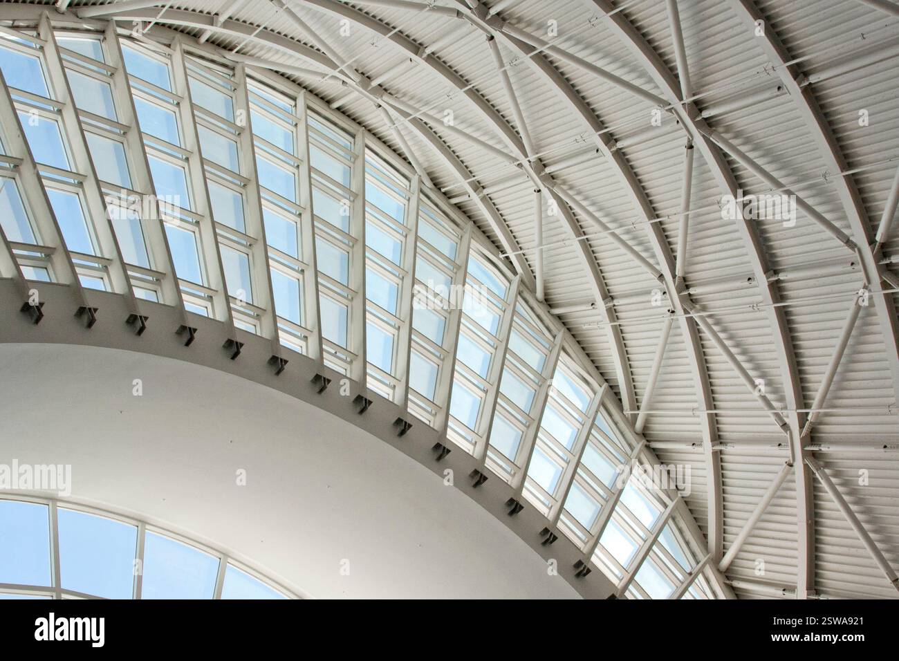 Grande edificio bianco con tetto curvo e molte finestre. L'edificio sembra essere una struttura moderna, con un design pulito e minimalista Foto Stock