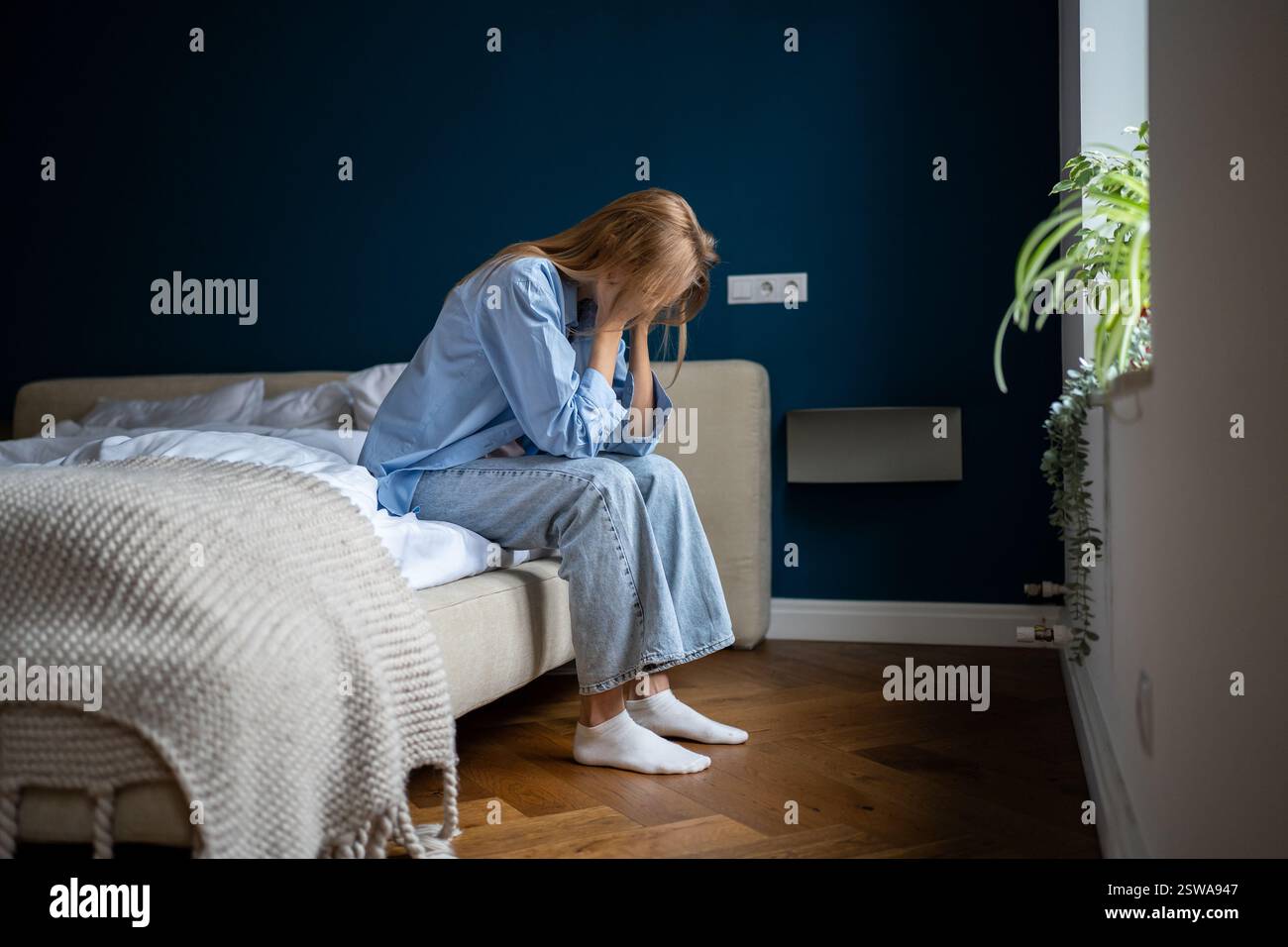 Depressa donna sola sedersi a letto a casa pensando a problemi, rompere, divorzio, sensazione di malessere Foto Stock