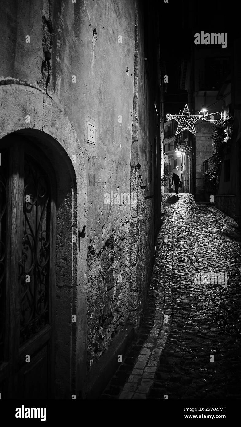 Un villaggio italiano abbandonato in una fredda notte invernale, dove il tempo sembra essersi fermato sotto il fiato bagliore degli antichi lampioni Foto Stock