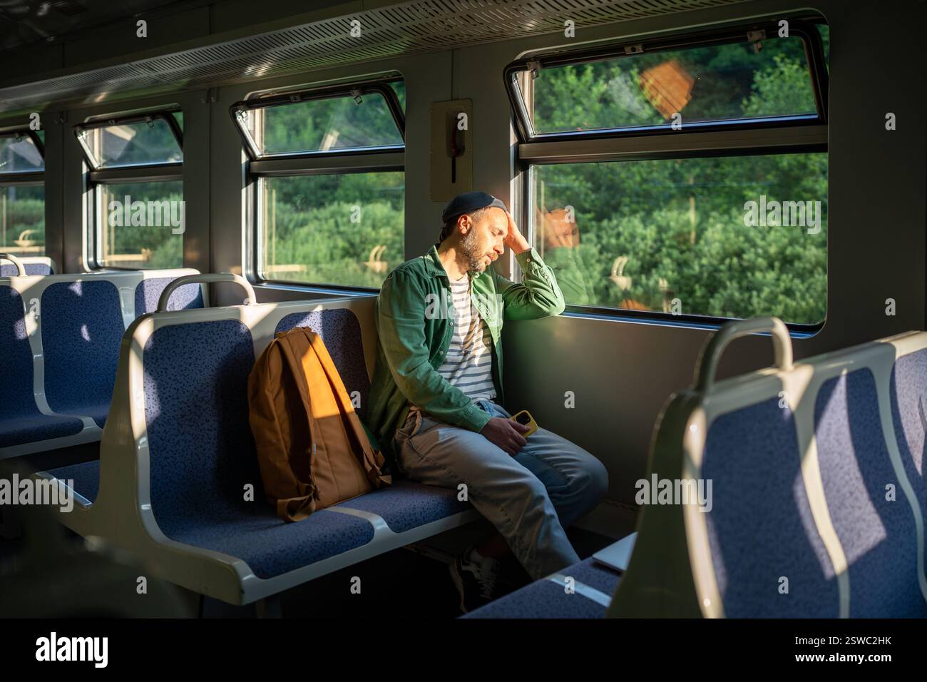 L'uomo esausto riposa in treno, dormendo durante gli spostamenti. Privazione del sonno di uomini sovraccarichi di lavoro Foto Stock