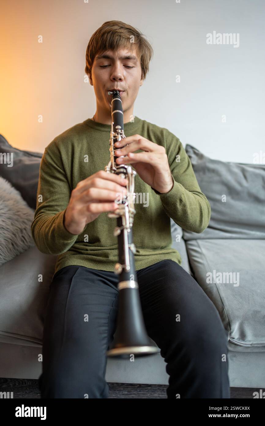 Suonatore di clarinetto. Clarinettista che suona flauto strumento a fiato a casa. Il tizio gioca a oboe Foto Stock