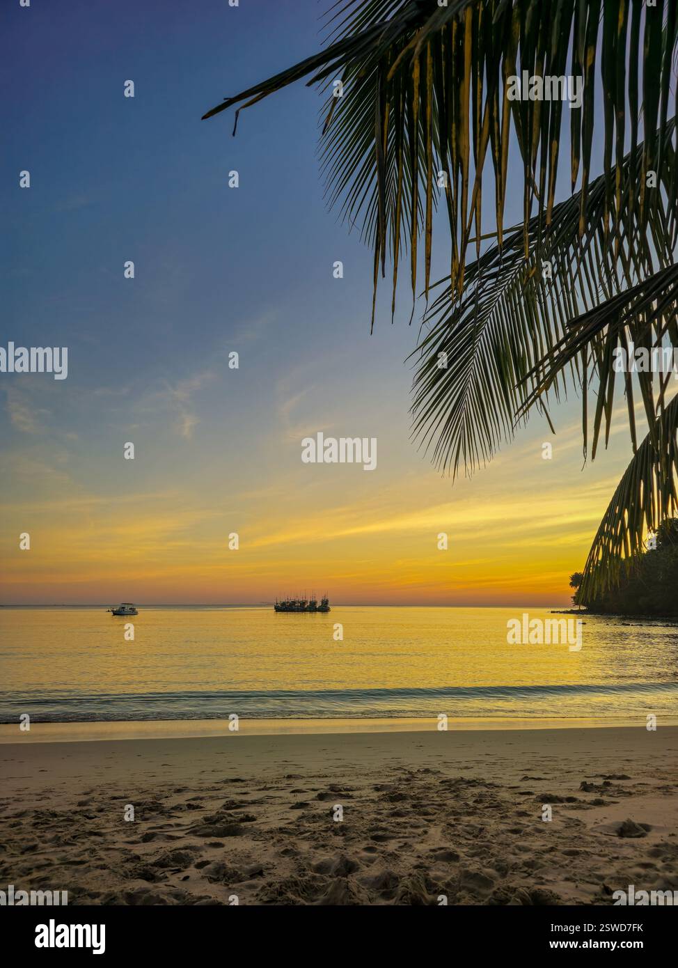 Tramonto vibrante sulla tranquilla spiaggia di Koh Kood in Thailandia con barche sagomate Foto Stock